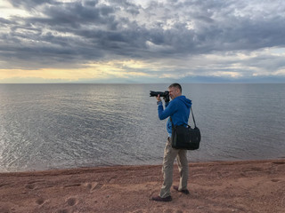 Obraz premium Рhotographer pointing camera at landscape on lake background.