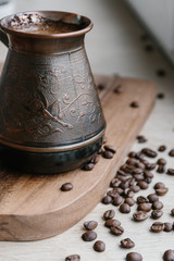 Turkish coffee pot and coffee beans on wooden board