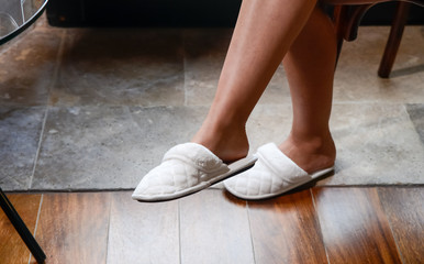 C&oacute;moda zapatilla pantufla colocada en el pie de una mujer sentada y con las piernas cruzadas en un d&iacute;a relajante