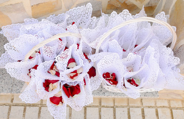 Conos hechos con papel blanco llenos de pétalos de rosas rojas, preparados para lanzar a los novios después de la boda.