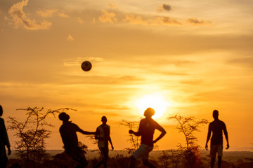people playing soccer in a rural setting at sunset
