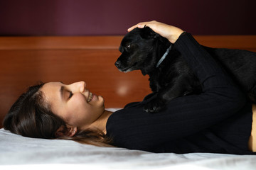 Woman lying in bed with a black dog.