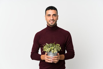 Young man over isolated white background taking a flowerpot