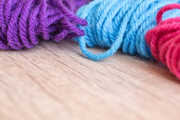 Obraz na płótnie Canvas Close up of a pink, purple and blue yarn balls on a wooden table with free space for text, soft selected focus.