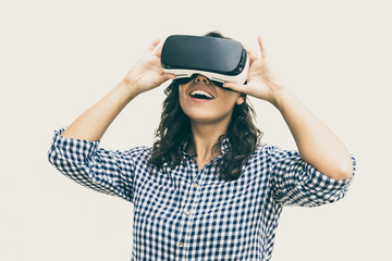 Happy student girl excited with VR game. Young woman in virtual reality headset standing isolated over white background. VR equipment concept