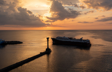 Naklejka na ściany i meble Lighthouse and a boat over the calm sea on sunset, sea, ship, lighthouse, sunset, waters, dawn, dusk, reflection