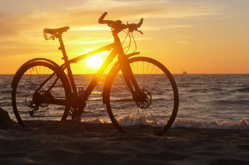 Fototapeta premium Bike and sunset by the sea. Black bike by the sea.