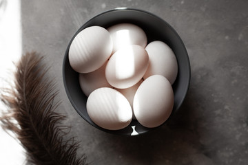 Plate filled with eggs.
The feather lies nearby.More than four eggs.Photo taken on concrete...