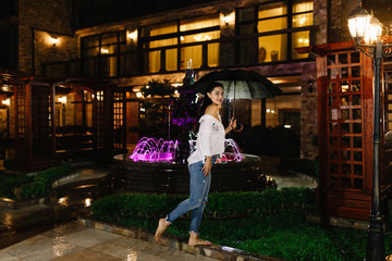 Portrait of beautiful young girl walking with umbrella under rain