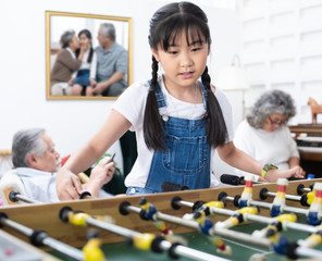 Young happy asian girl playing soccer table game together happiness. Grandmother and grandfather sit relax in living room in home after retirement daily lifestyle. Happy leisure time family concept.