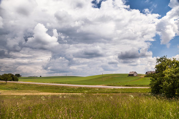 Naklejka premium Green meadows, a wooden rural house on a hill