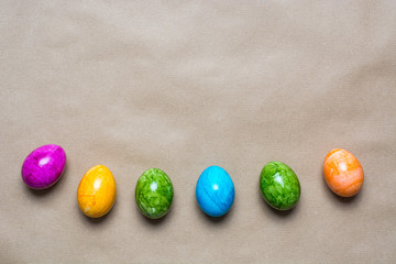 Border of easter eggs in different colors on the bottom on brown paper background