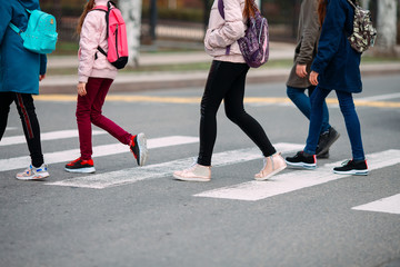 School children cross the road in medical masks. Children go to school.
