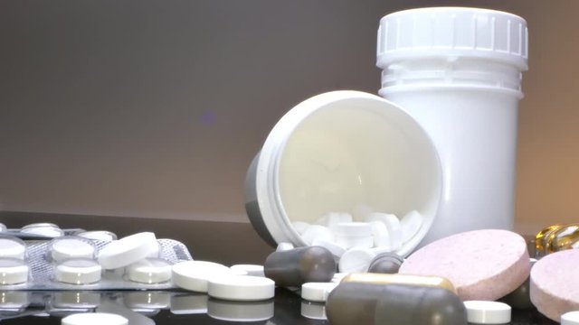 treatment concept, medicines in packs and jars and pills scattered on a black table