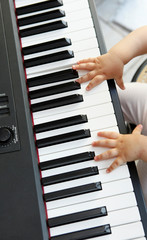 dettagli di mani di un bambino  che suonano un pianoforte 