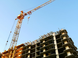 Industrial crane near building against blue sky. Construction site.