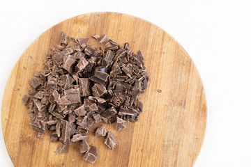 Flat lay above grated dark cooking chocolate on the wooden board.