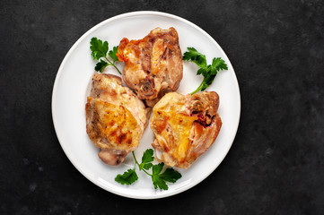 grilled chicken thighs on a white plate with spices on a stone background