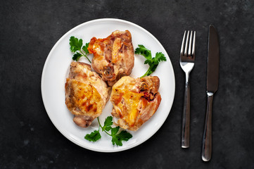 grilled chicken thighs on a white plate with spices on a stone background