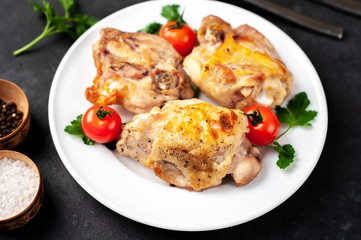grilled chicken thighs on a white plate with spices on a stone background