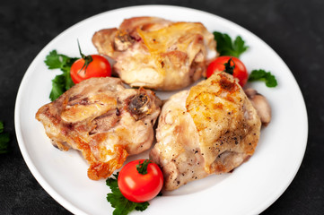 grilled chicken thighs on a white plate with spices on a stone background