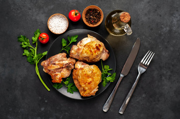 grilled chicken thighs on a black plate with spices on a stone background