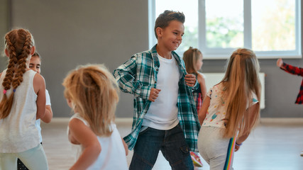 Having fun. Group of positive children learning a modern dance in the dance studio. Choreography...