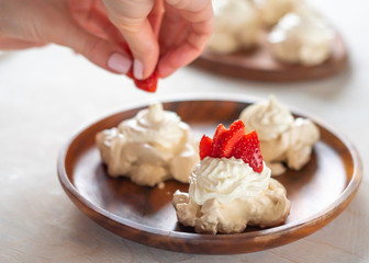 the process of creating Pavlova dessert, decorating the meringue with strawberries
