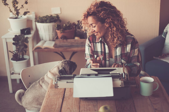 Cheerful Beautiful Woman With Her Lovely Dog Pug At Home While Write For Work With Old Typewriter And Enjoy The Indoor Leisure Activity With Cup Of Tea - Concept Of Job And Best Friend Animal