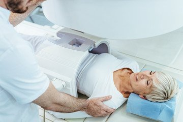 Smiling senior woman talking to radiologist while having abdomen MRI scan at clinic.