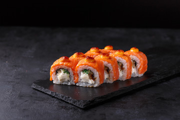 Sushi rolls with salmon, eel, cremette cheese, cucumber, spicy sauce on black background