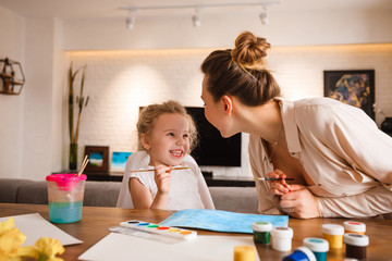 Mom with a child paint in the kitchen.