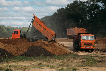 three orange dump trucks at a construction site with sand © dobrovizcki