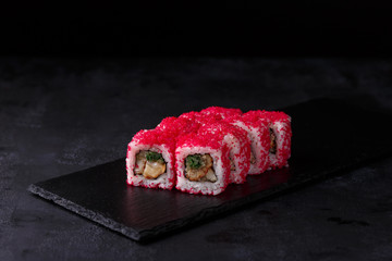 Traditional fresh japanese sushi rolls on a black stone California ebi . Roll ingredients:eel, cucumber, red tobik caviar, nori, rice.