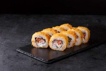 Sushi rolls with salmon, eel, shrimp, nori, cremette cheese, cucumber on a black background.