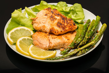 Plate with salmon,asparagus,salad and lemon