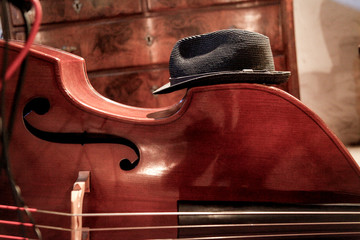 Dettaglio di un violoncello con sopra un cappello da musicista