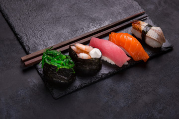 close up of sashimi sushi set with chopsticks on black background