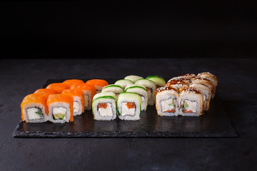Sushi set with various kinds of rolls on a black background