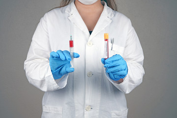 Doctor holding syringe in one hand and blood tube in the other