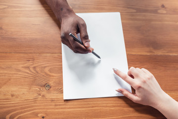 Obraz premium Analizing together. Close up of african-american male and caucasian female hands, working in office. Concept of business, finance, job. Copyspace for advertising. Education, communication and