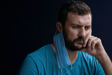 Worried young doctor or nurse man wearing medical face mask, studio portrait. Man wearing face mask during coronavirus outbreak. Virus spread flu prevention quarantine