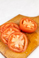 Sliced fresh tomato on the wooden cutting board with copy space