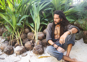 fashion guy with dreadlocks in tropical coconut palms smiling