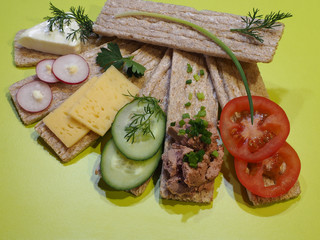 Different sandwiches with rye bread crackers, slices of cheese, cream cheese, tomatoes, cucumbers, radishes, spicy herbs on a bright background. Tasty snacks for healthy and proper nutrition, top view