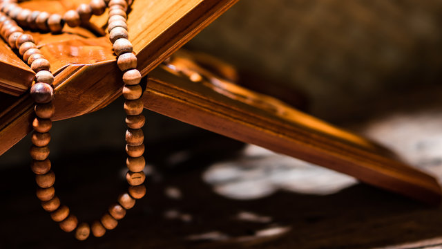 Islamic prayer beads or tasbih on rihal or quran book stand made from carved wood. It is suitable for background of Ramadan-themed design concepts or other Islamic religious events.