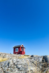Beautiful red cottage in the Swedish Archipelago. Blue Sky.