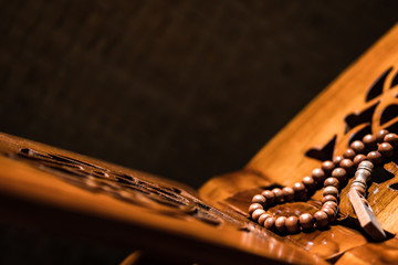 Islamic prayer beads or tasbih on rihal or quran book stand made from carved wood. It is suitable for background of Ramadan-themed design concepts or other Islamic religious events.