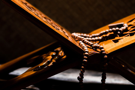 Islamic prayer beads or tasbih on rihal or quran book stand made from carved wood. It is suitable for background of Ramadan-themed design concepts or other Islamic religious events.