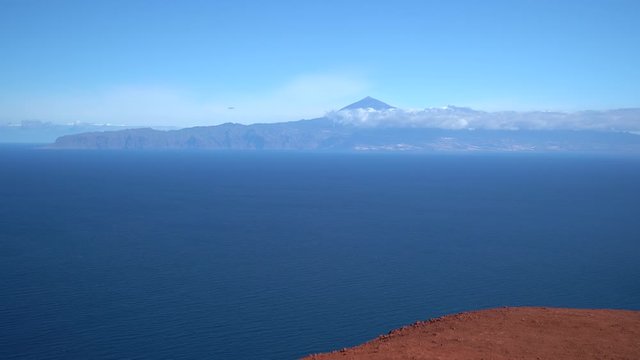 La Gomera - Blick &uuml;ber das Meer auf die Insel Teneriffa, aufgenommen von der roten Erde am Aussichtspunkt Mirador de Abrante oberhalb von Agulo